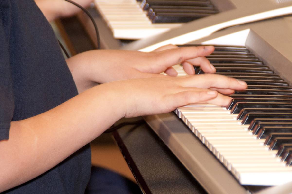 Close up of hands playing an electronic keyboard piano.